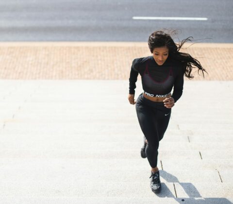 woman in black long sleeve shirt and black pants running on gray concrete road during daytime